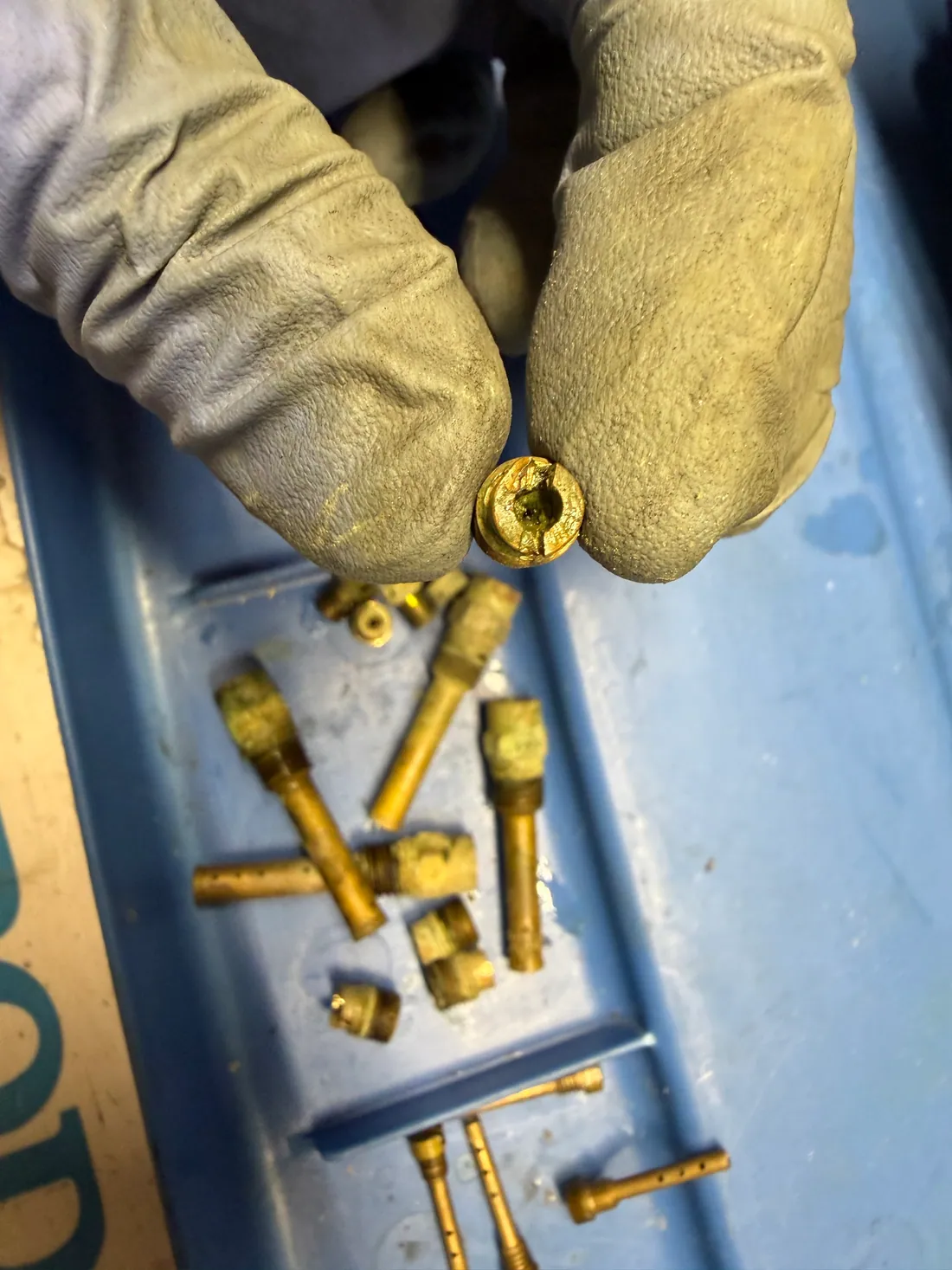 Damaged brass carburetor jet removed during motorcycle repair